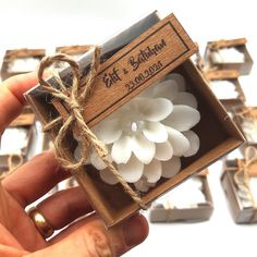 a hand holding a box with some white flowers in it