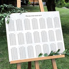 an easel with seating cards and greenery on it