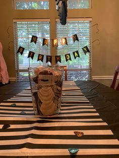 a birthday party table set up with black and white striped cloths, paper streamers and decorations