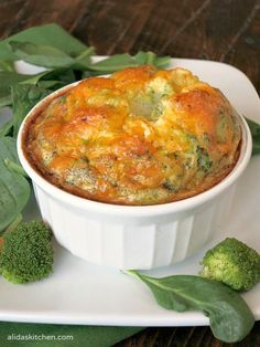 broccoli and cheese casserole in a white dish with green leaves around it