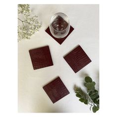 four square coasters on top of a table next to a vase with flowers in it