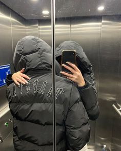 a person taking a selfie in front of an elevator door with their cell phone