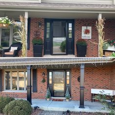 an outside view of a brick building with two black doors and plants on the windows