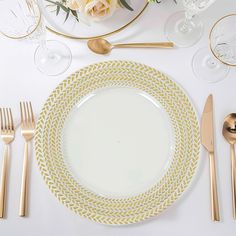 a table set with gold and white plates, silverware, and rose centerpieces