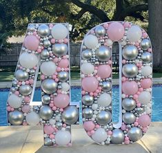 the letters are made out of balloons and balls in pink, silver and white colors