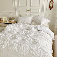 a bed with white comforters and pillows in a room