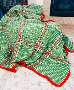 a green and red blanket sitting on top of a couch