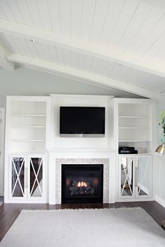 a living room with a fireplace and white bookcases