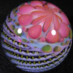 a close up of a decorative object on a black surface with lights in the background