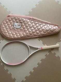 a pink hello kitty tennis racket and case on a white surface with grey squares