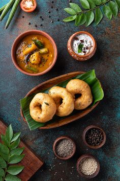 some food that is on a plate and in bowls next to other dishes with spoons