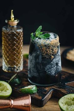 a glass filled with ice and mint on top of a wooden cutting board