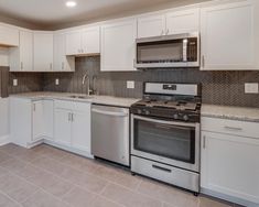 a kitchen with stainless steel appliances and white cabinets