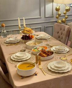 a dining room table is set with plates, bowls and silverware for an elegant meal