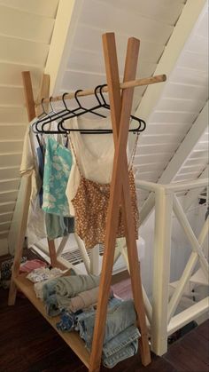 clothes are hanging on racks in the corner of a room with white walls and wooden floors