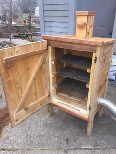 a wooden cabinet sitting on the side of a road next to a building with an open door