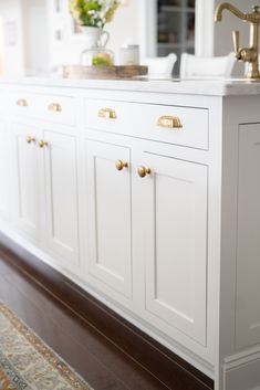 a kitchen with white cabinets and gold pulls on the handles is pictured in this image