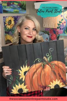 a woman holding up a piece of art that has sunflowers painted on it