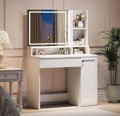 a white dressing table with a mirror and lights on the top shelf next to a potted plant