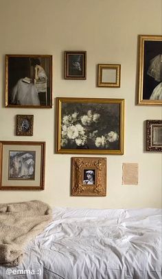 a bed with white sheets and pictures on the wall