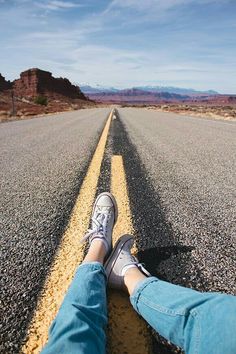 someone's feet on the side of an empty road with words written across it