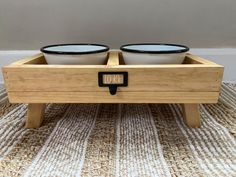 two bowls sit in the middle of a wooden tray on top of a carpeted floor