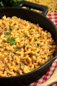 a skillet filled with macaroni and cheese on top of a checkered table cloth