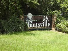 a sign that is in the grass with trees behind it and text overlay reads huntsville, tx