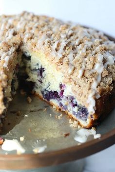 a blueberry crumb cake is cut in half on a metal platter with one slice taken out