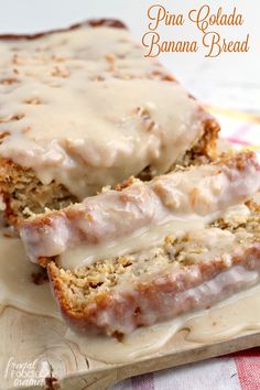 two slices of banana bread with icing on a cutting board next to a fork