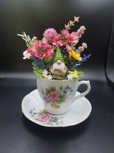 a teacup with flowers in it sitting on a saucer next to a black background