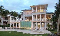 a large white house sitting on top of a lush green field next to a swimming pool