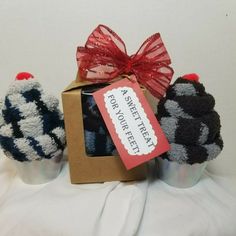 three knitted mittens sitting in front of a box with a tag on it