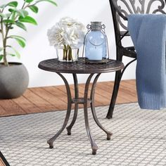 a small table with flowers on it next to a blue chair and potted plant