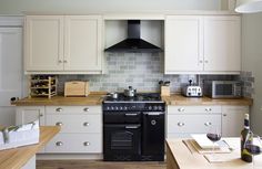 a black stove top oven sitting inside of a kitchen next to wooden counter tops and white cabinets