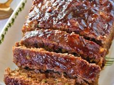 sliced meatloaf on a white plate with green sprigs