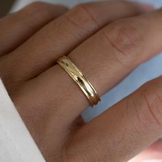 a woman's hand with a gold ring on top of her finger and the other hand holding it