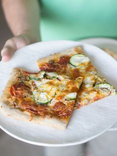 two slices of pizza sitting on top of a white plate with cucumber toppings