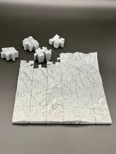 a piece of puzzle sitting on top of a table next to pieces of white paper