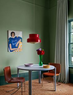 a dining room with green walls and colorful artwork on the wall, along with two chairs