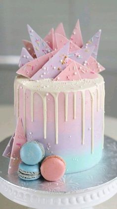 a colorful cake with icing dripping down the side and decorations on top, sitting on a plate