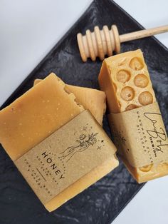 two pieces of soap sitting on top of a black plate next to a honey comb