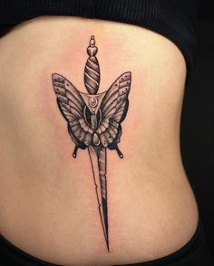 a woman's stomach with a knife and butterfly tattoo on the side of her belly