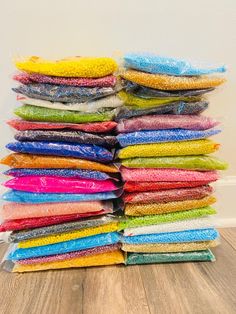 a stack of multicolored cloths sitting on top of a wooden floor next to a white wall