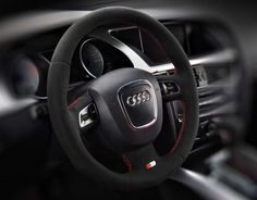 the interior of an audi car with red stitching and steering wheel cover on it