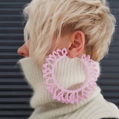 a woman with blonde hair wearing large pink crochet hoop earrings on her neck