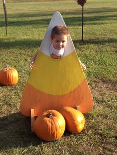 a little boy sitting in a fake pumpkin shaped like a boat and some pumpkins