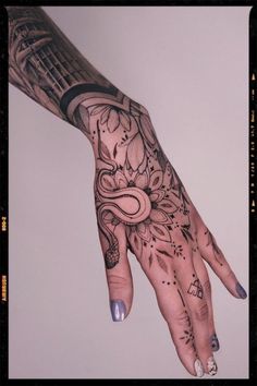 a woman's hand with tattoos on it and an intricate design in the middle