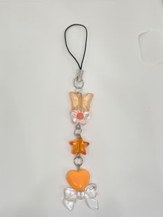 a key chain with an orange and white butterfly on it's side, hanging from a black cord