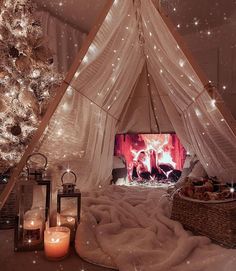 a white tent with lights and candles in front of a christmas tree that is lit up